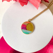 Collier rond en cuir marqueterie fait main par Manali, bijou artisanal coloré
Pendentif cuir recyclé technique marqueterie - fabrication française. soleil